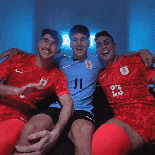 three soccer players are posing for a picture and one of them has the number 23 on his shirt