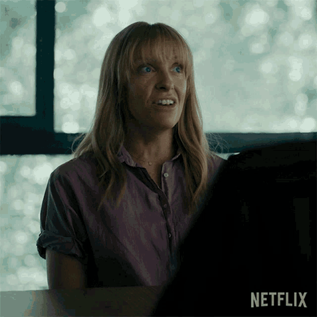 a woman is sitting at a desk with a netflix logo in the corner