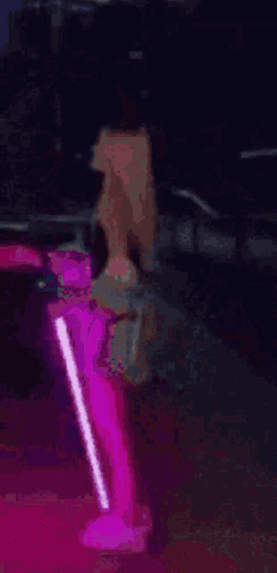 a person is standing next to a pink chair in the dark .