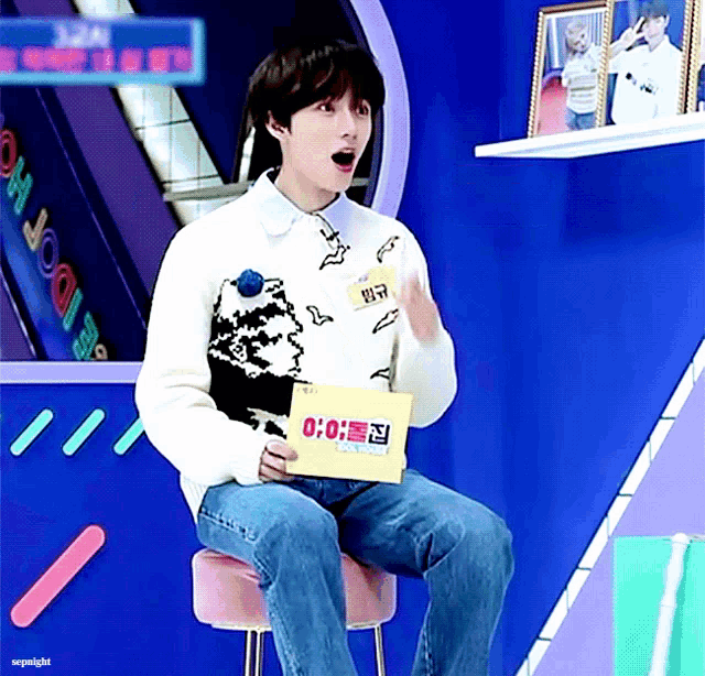 a man is sitting on a stool holding a box that says 0:00