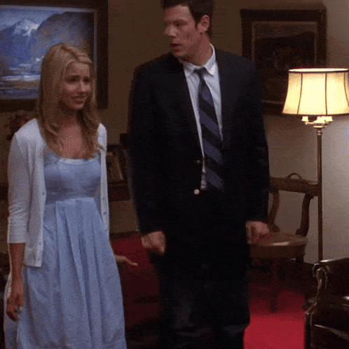a man in a suit and tie stands next to a woman in a dress