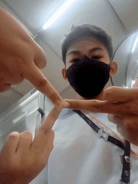 a man wearing a black face mask is making a peace sign