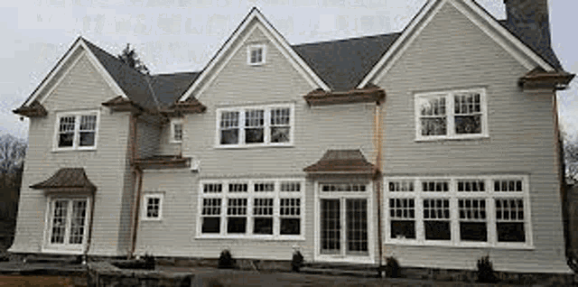 a large white house with a lot of windows and a chimney on top of it .