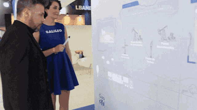 a woman in a blue galileo dress is standing next to a man