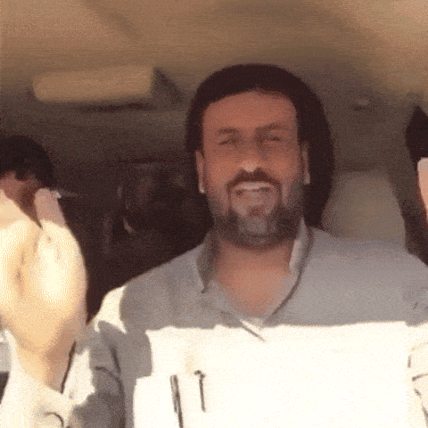 a man with a beard is sitting in the back seat of a car making a funny face .