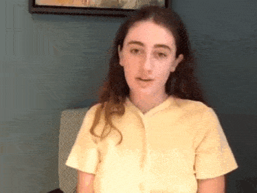 a woman in a yellow shirt sits in a chair