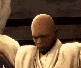a bald man is standing in front of a wall with his arms outstretched .