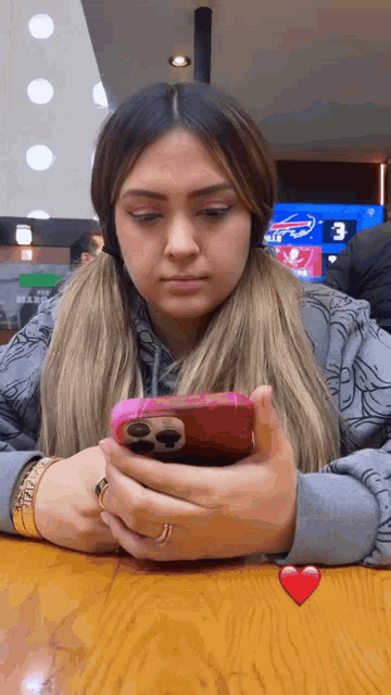 a woman sitting at a table looking at her phone