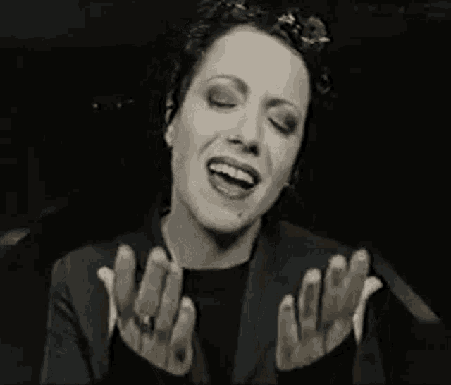a black and white photo of a woman singing into a microphone .