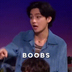 a man in a blue shirt is standing in front of a group of people and the word boobs is above him .