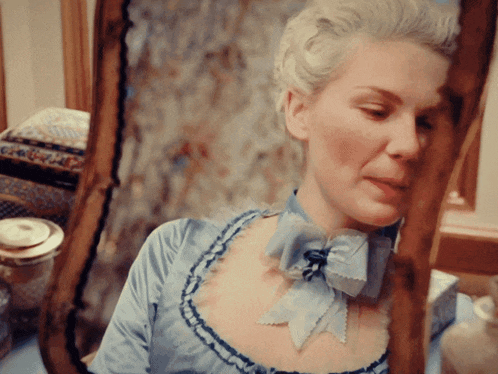 a woman in a blue dress looks at herself in the mirror