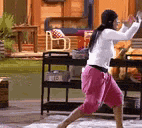 a woman in a white shirt and pink shorts is dancing in a room .