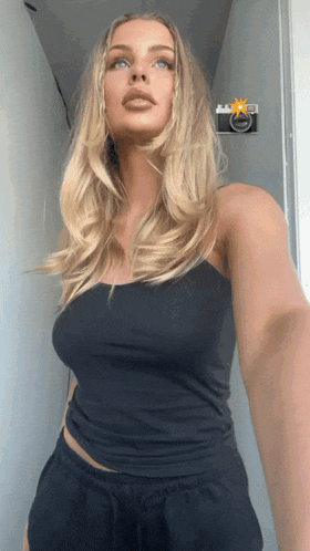a woman in a black tank top takes a selfie