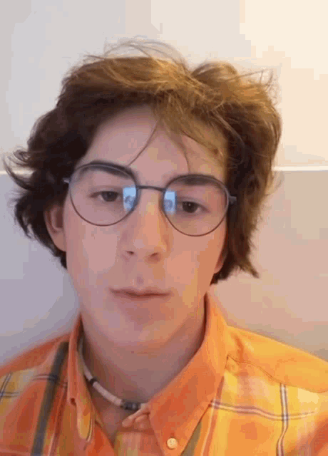 a young man wearing glasses and a plaid shirt