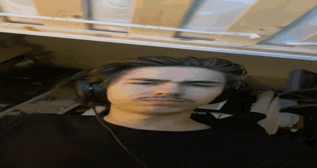 a man wearing headphones and a black shirt with a triangle on the front