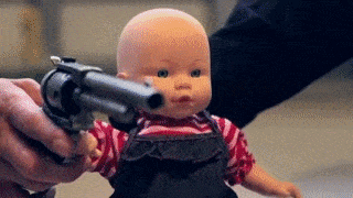 a person is pointing a revolver at a baby doll
