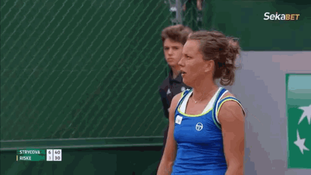 a woman is standing on a tennis court with her hands on her hips and a sign in the background that says sekabet