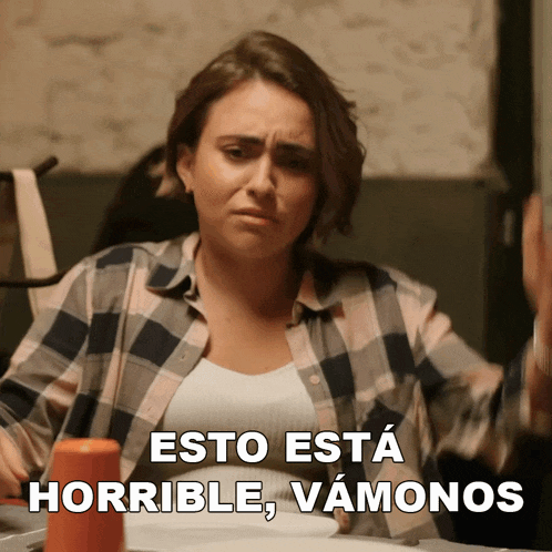 a woman sitting at a table with the words esto esta horrible vamonos written above her