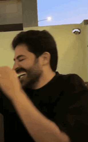 a man with a beard is laughing while holding something in his hand