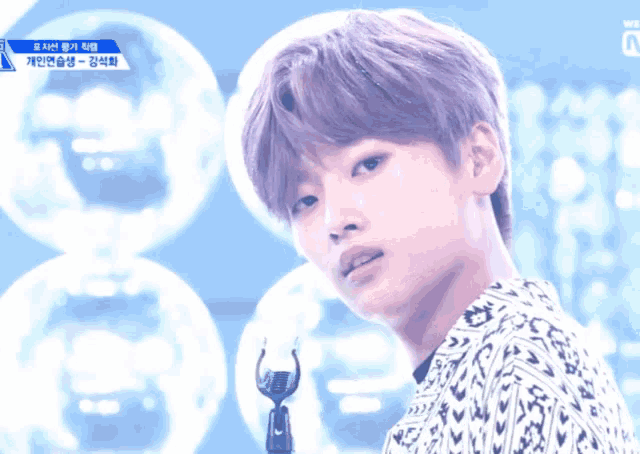 a young man stands in front of a microphone with a blue sign that says we on it