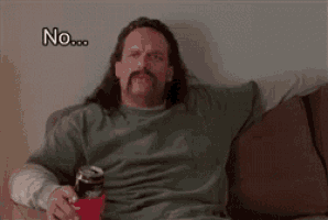 a man with long hair and a mustache is sitting on a couch holding a can of soda and saying no .