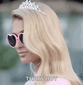 a blonde woman wearing a tiara and sunglasses is standing in front of a building .