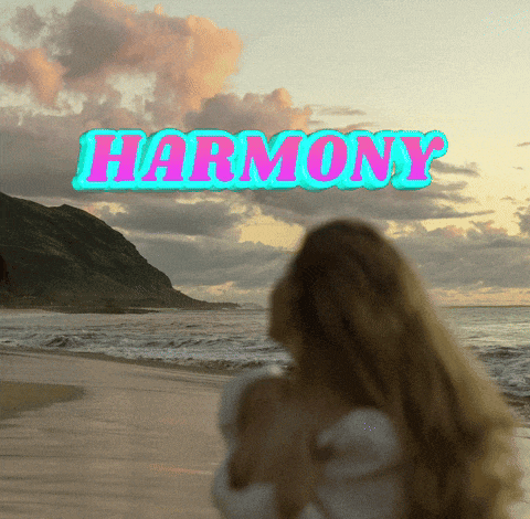 a woman standing on a beach with the word harmony written above her