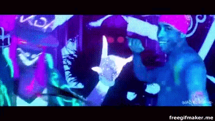 a man in a pink hat is standing in front of a colorful background in a club .