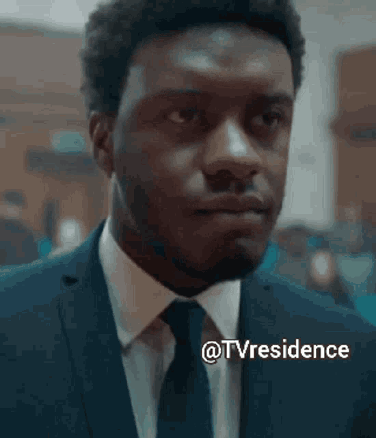 a man in a suit and tie is looking at the camera with the words @tvresidence above him