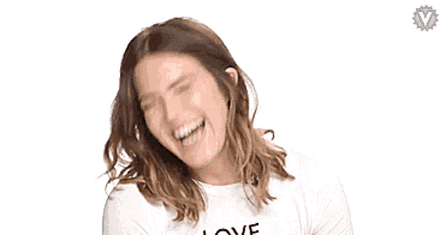 a woman is laughing and wearing a white shirt that says love