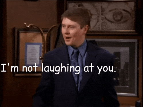 a man in a suit and tie says i 'm not laughing at you and i 'm laughing at him