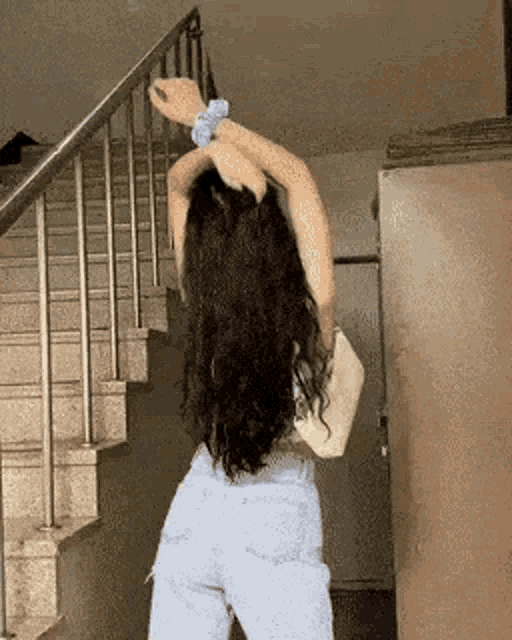 a woman is standing on a set of stairs stretching her arms .