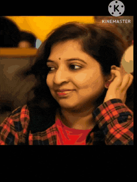 a woman in a plaid shirt is smiling and looking at the camera with a kinemaster logo in the corner
