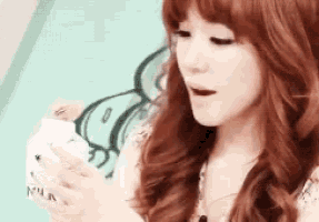 a woman with red hair is holding a cup of milk