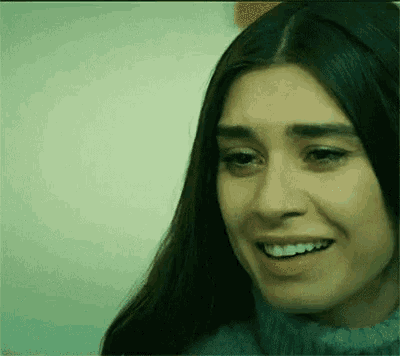a close up of a woman 's face smiling and looking at the camera .