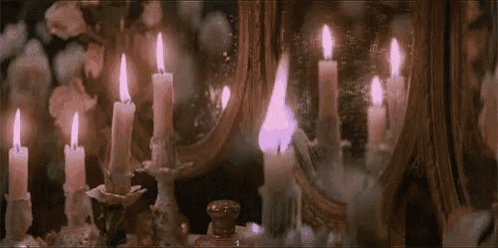 a bunch of lit candles on a table in front of a mirror .