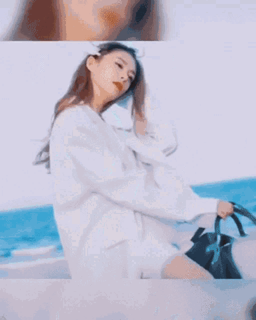 a woman in a white jacket is riding a white horse on the beach