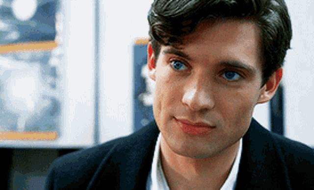 a man with blue eyes is wearing a black coat