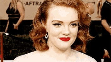 a close up of a woman 's face with red lipstick and earrings .