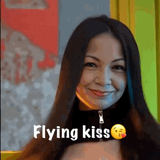 a woman with long hair is smiling with the words flying kiss above her .