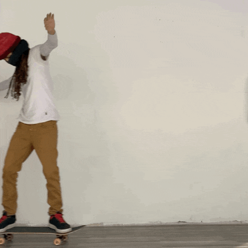 a person wearing a red hat and a white shirt rides a skateboard