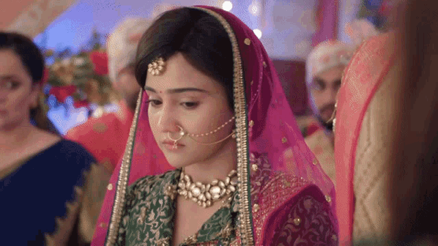 a woman with a nose ring is wearing a pink and green dress