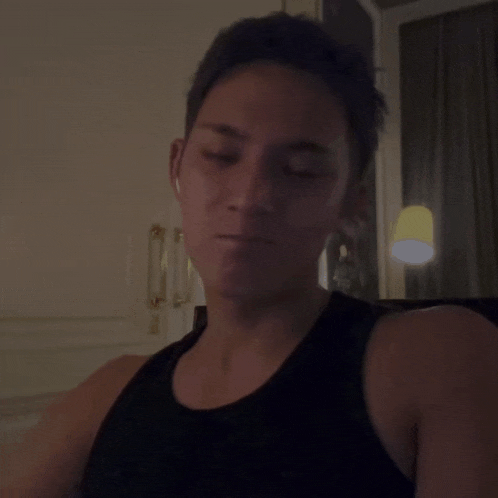 a man wearing a black tank top is looking at the camera