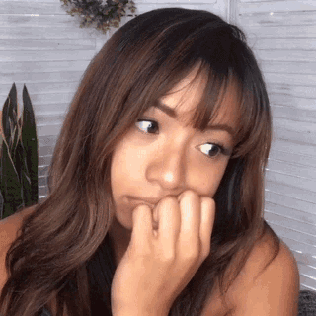 a woman covering her mouth with her hand and making a funny face
