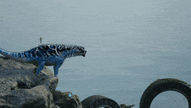 a blue lizard is standing on a rock near a tire