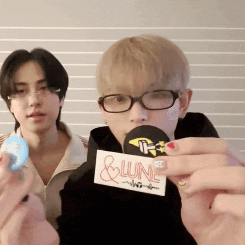 a man with glasses holds a sticker that says & lunc