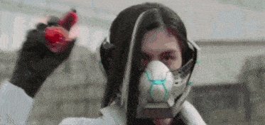 a woman in a gas mask is holding a red object in her hand .