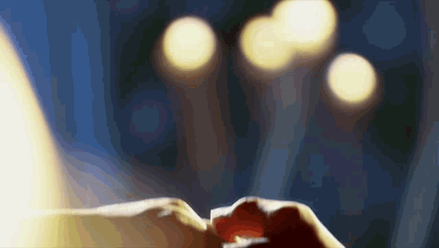 a close up of a person 's hands with a blurry background of lights behind them .