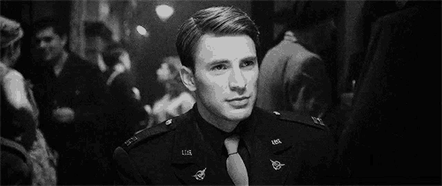 a man in a military uniform and tie is looking at the camera .