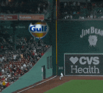 a baseball player is leaning against a wall on a field .